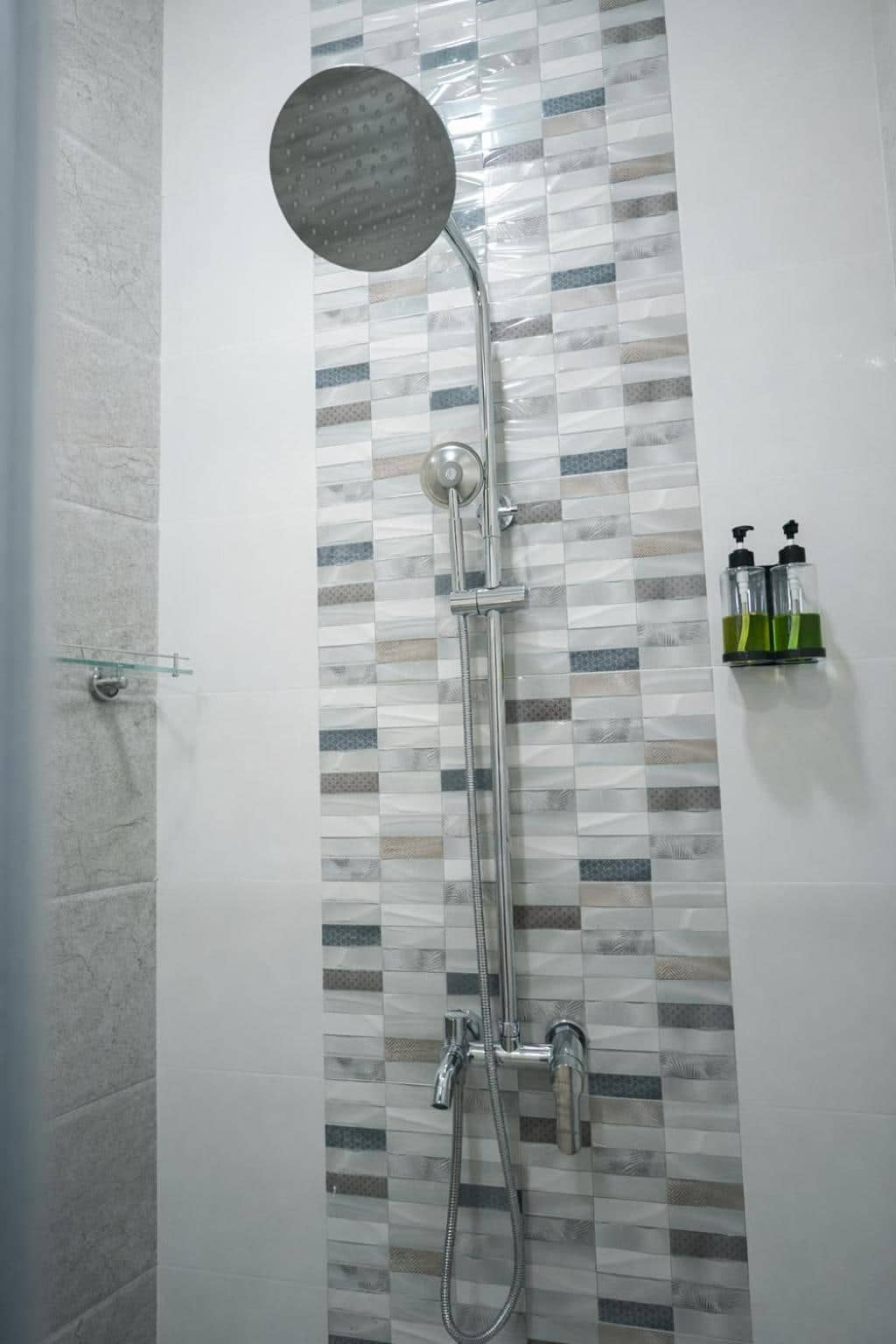 Rain shower with mosaic tiled wall and toiletries