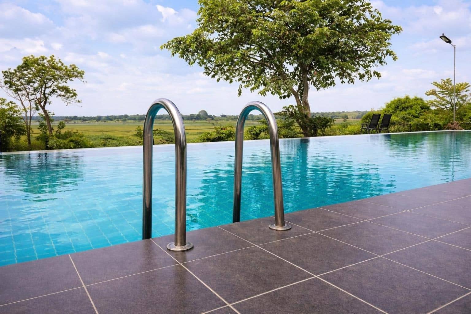 Lakeside infinity pool with pool ladder, shade trees and paddy fields