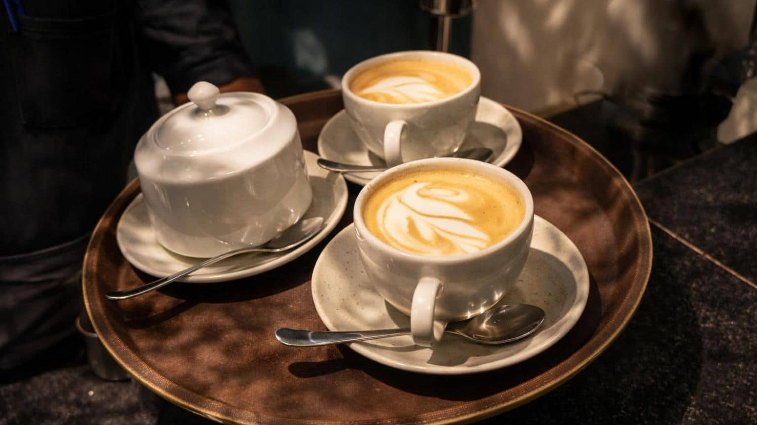 Two cappuccinos with latte art on a copper tray
