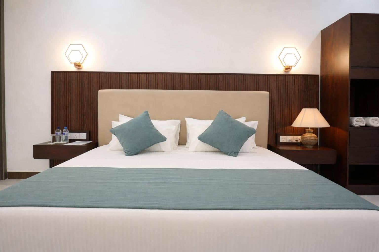 Queen bed dressed in white linen with sage cushions